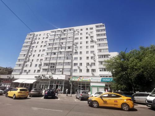 Un gran edificio blanco con coches aparcados delante. en Sunset Bucharest, en Bucarest