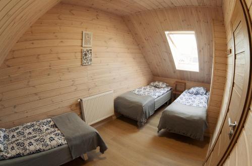 a attic room with two beds and a window at Przystanek Tykocin - domki gościnne w sercu Podlasia in Tykocin