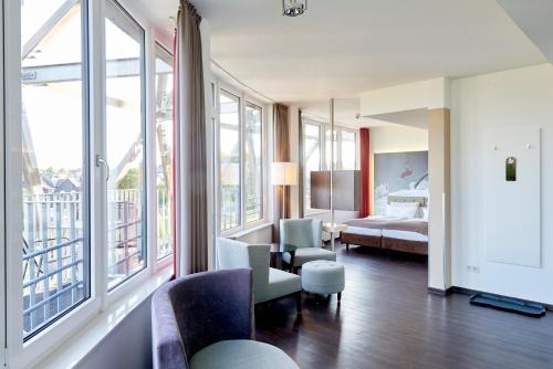 ein Hotelzimmer mit einem Schlafzimmer mit einem Bett und Fenstern in der Unterkunft Hotel Oversum Winterberg Ski- und Vital Resort in Winterberg