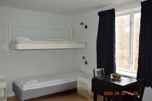 a bedroom with a bed and a desk and a window at STF Kapellskär Hostel in Gräddö