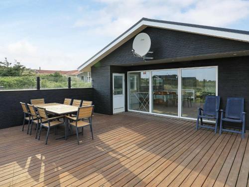 a wooden deck with a table and chairs on it at 8 person holiday home in Ringk bing in Ringkøbing