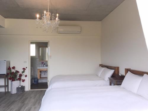 two beds in a bedroom with a chandelier at 稻哪趣田園民宿 平價villa in Dongshan