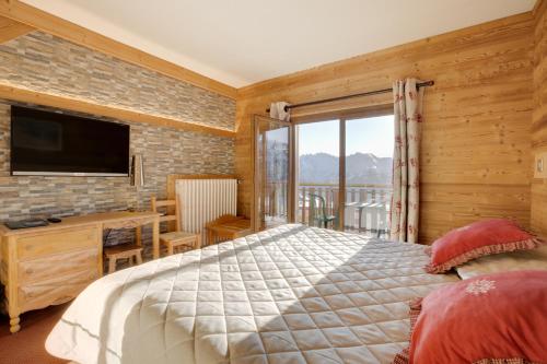 a bedroom with a bed and a tv and a balcony at Le Castillan in L'Alpe-d'Huez