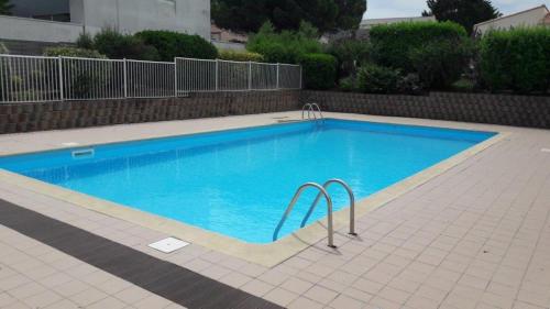 une grande piscine avec de l'eau bleue dans une cour dans l'établissement Appart Must1 Minimes avec Piscine, à La Rochelle