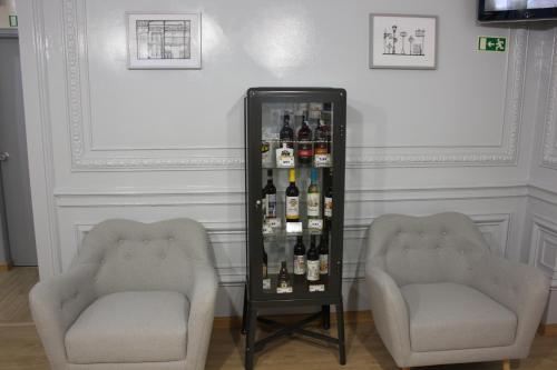 two chairs and a display case with bottles of wine at O Elétrico Guesthouse in Lisbon