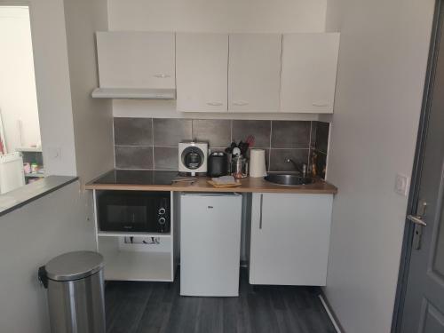 una piccola cucina con armadi bianchi e lavandino di Calme 2 Pièces en Duplex a Aufferville