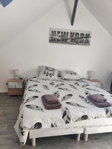 Schlafzimmer mit einem Bett mit einer schwarzen und weißen Bettdecke in der Unterkunft Calme 2 Pièces en Duplex in Aufferville