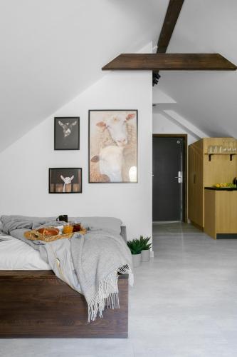 a white bedroom with a bed and pictures on the wall at Aparthotel Narciarska 2 in Korbielów