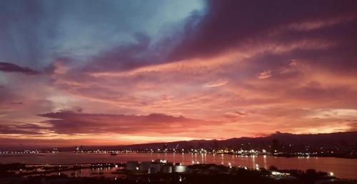 a sunset over a body of water with a city at BH Mangrove Condos in Mactan