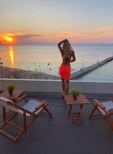 a woman in a red skirt standing on a roof with the sunset at Vento di Mare in Perea