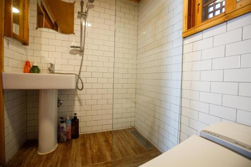 a bathroom with a sink and white tiled walls at GaEunChae 2 in Jeonju