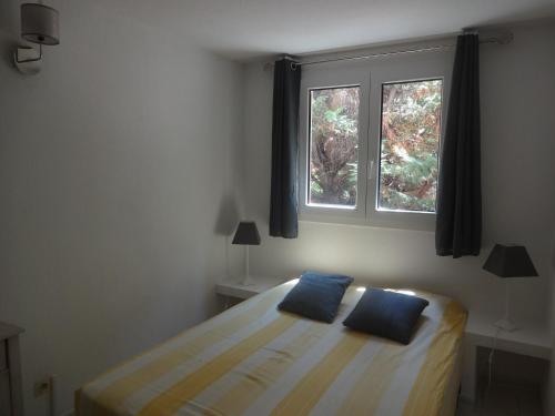 une chambre avec un lit et deux fenêtres dans l'établissement Residence Pezza Cardo, à Porto-Vecchio