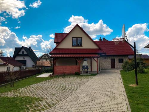 a house with a red roof on a brick road at Agroturystyka Kasia in Podwilk