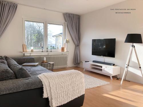 a living room with a couch and a flat screen tv at Das Penthouse am Meer - Logenplatz an der Förde - in Glücksburg