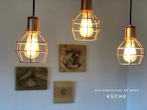 three lights hanging from a wall in a room at Das Penthouse am Meer - Logenplatz an der Förde - in Glücksburg