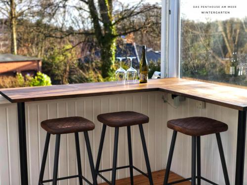 a bar with two stools at a counter with a window at Das Penthouse am Meer - Logenplatz an der Förde - in Glücksburg
