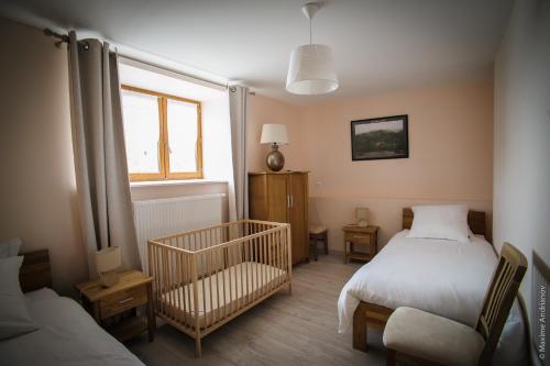 a bedroom with two beds and a crib and a window at La Bégude D'Amalthée in Vernay
