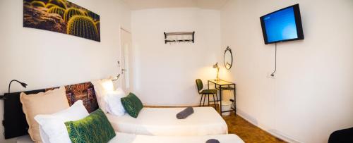 a living room with a white couch and a tv at Alagoa Terrace Guesthouse in Faro