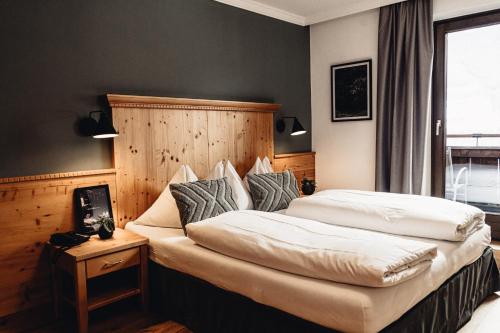 a bedroom with a large bed with a wooden headboard at Designhotel Sonnhof by Vitus Winkler in Sankt Veit im Pongau