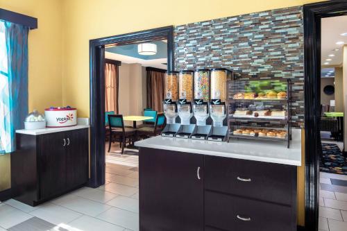 a restaurant with a counter with food on it at La Quinta by Wyndham Oxford - Anniston in Oxford