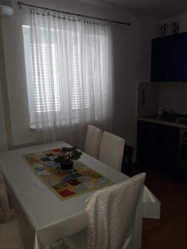 a white table and chairs with a table and a window at Apartments Sindi in Lopar