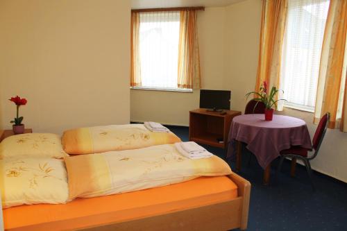 a hotel room with two beds and a table at Hotel Hubbert in Castrop-Rauxel