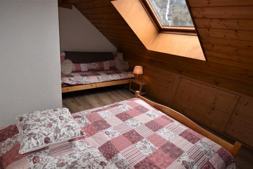 1 dormitorio en el ático con cama y ventana en VAUJANYLOCATIONS - Claret II Apt 12, en Vaujany