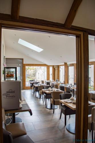 Un comedor con mesas y sillas y ventanas. en LOGIS HOTEL - Le Relais Saint Vincent, en Ligny-le-Châtel