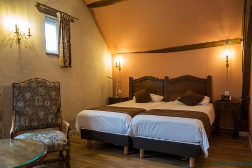 een slaapkamer met 2 bedden en een tafel en een stoel bij LOGIS HOTEL - Le Relais Saint Vincent in Ligny-le-Châtel