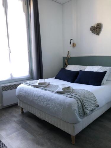 a bedroom with a large bed with blue pillows at Le Cottage in Villers-sur-Mer