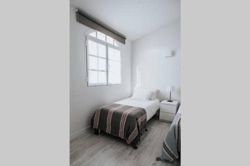 a white bedroom with a bed and a window at Chalet pareado a 5 minutos andando de la playa in La Garita