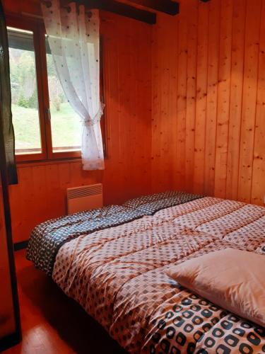 Ce lit se trouve dans une chambre en bois dotée d'une fenêtre. dans l'établissement CHALET LES EPILOBES, à Lamoura
