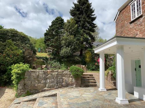 a brick house with a stone wall next to a yard at Boscundle Manor in St Austell