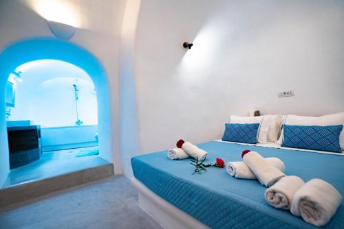 a bedroom with a blue bed with towels on it at Bonita Santorini Cave in Éxo Goniá