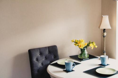 una mesa con un jarrón de flores y una silla en corby house, en Ardara