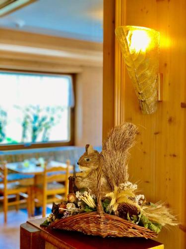a statue of a squirrel in a basket on a table at Hotel B&B Lorenzini Ski in Selva di Cadore
