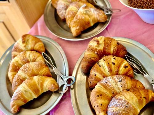 three plates of pastries and croissants on a table at Hotel B&B Lorenzini Ski in Selva di Cadore