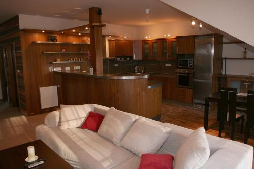 a living room with a white couch and a kitchen at Apartmán Bílá Hora - Roudná in Plzeň