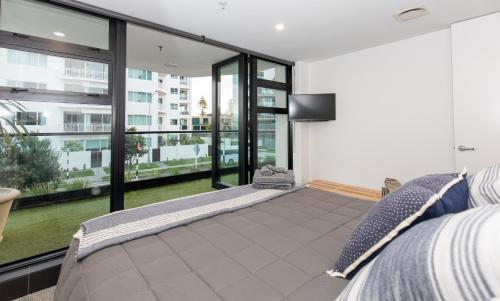 a bedroom with a bed and large glass windows at Ocean Eleven 22 in Mount Maunganui