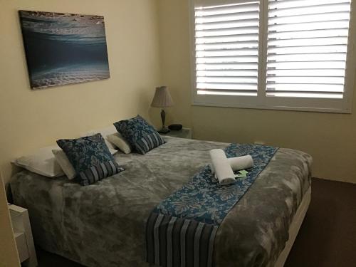 a bedroom with a bed with two pillows and a window at Sandcastles Holiday Apartments in Coffs Harbour