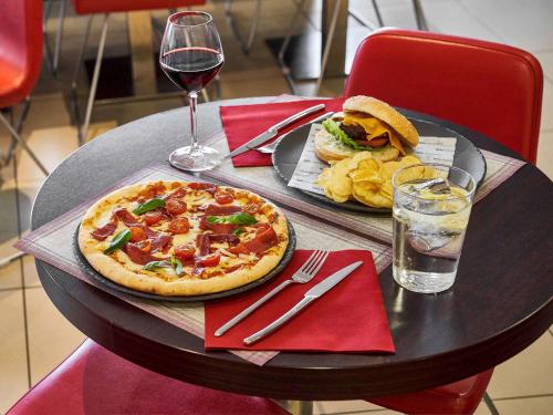 a table with a pizza and a sandwich and a glass of wine at Ibis Barcelona Meridiana in Barcelona