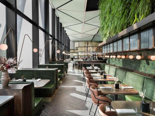 a restaurant with tables and chairs and plants at Novotel Auckland Airport in Auckland
