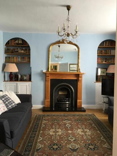 a living room with a fireplace and a mirror at Woodbine Cottage in Tenby