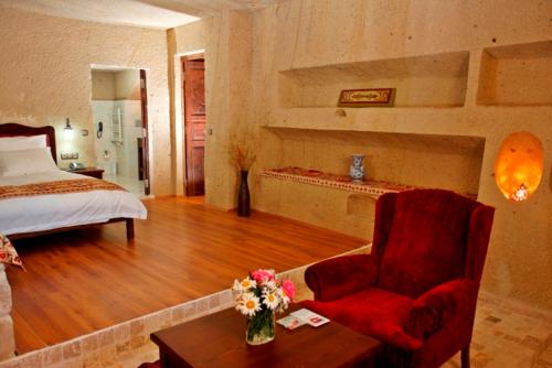 a bedroom with a bed and a chair and a table at Dreams Cave Hotel in Ortahisar