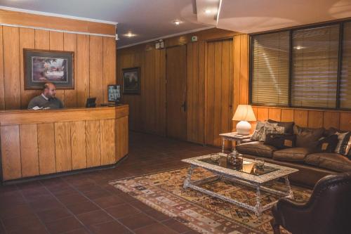 a man standing at a reception desk in a living room at Alessandria Apart - Coronel Pereira in Santiago