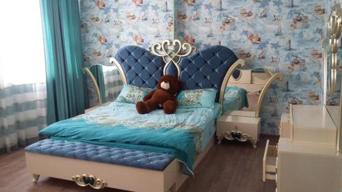 un osito de peluche sentado en una cama azul en una habitación en Family holiday home. en Qusar