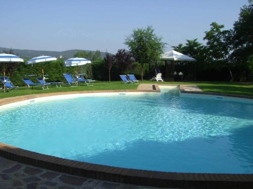 a large blue swimming pool with chairs and umbrellas at Agriturismo La Selva in Siena