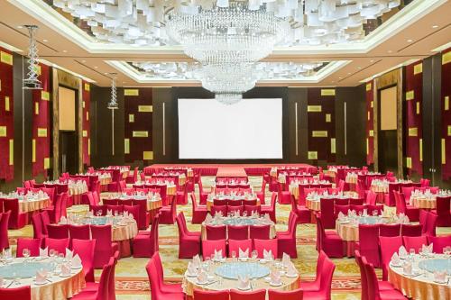a large banquet hall with red chairs and a white screen at Crowne Plaza Guangzhou Huadu by IHG - Free Shuttle bus between hotel to Exhibition Center During Canton Fair in Guangzhou