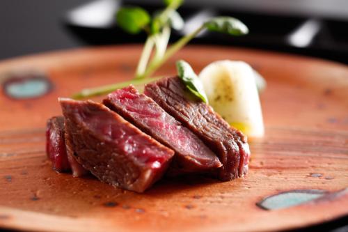 a piece of meat on a plate on a table at The Shiroyama Terrace Tsuyama Villa in Tuyama