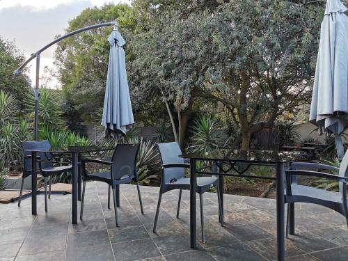a table with chairs and an umbrella on a patio at Aerotropolis Guest Lodge in Kempton Park